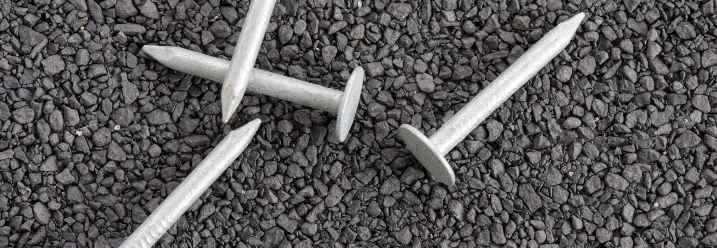 Fünf Dachpappennägel auf Schotter.